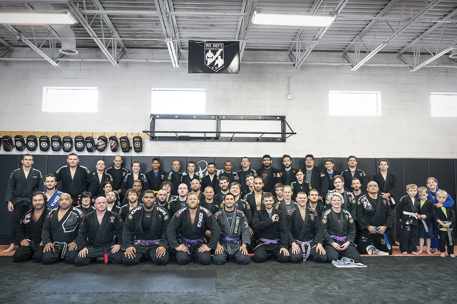 The Victorious MMA academy lined up in rows for a group photo, adults and children in dark gis with instructors at the front.
