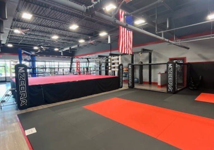 Champion Jiu Jitsu & MMA gym interior — mat space with boxing ring and MMA cage, Chesterfield, MI